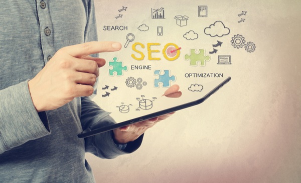 hands using a tablet, surrounded by a cloud of tech icons and the words "SEO: Search Engine Optimization"